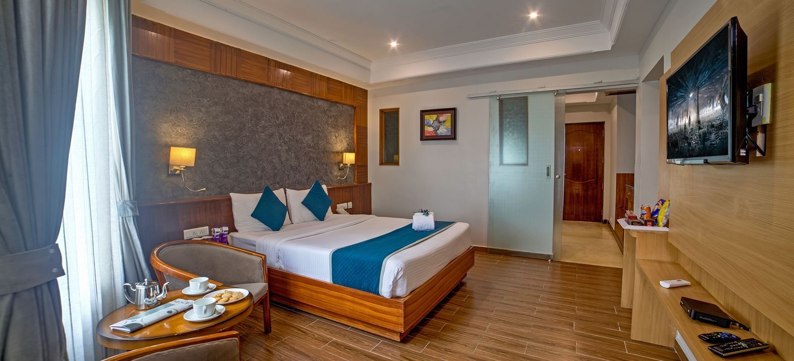 Well-appointed guest room with wooden flooring, modern furnishings, and a cosy seating area at Ilara Hotels & Spa, OMR, Chennai