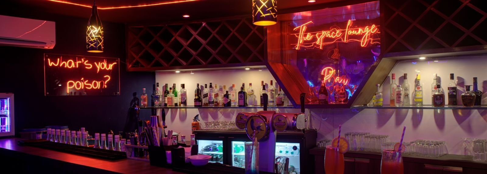Stylish bar counter with colourful lighting and illuminated drink display at Ilara Hotels & Spa, OMR, Chennai