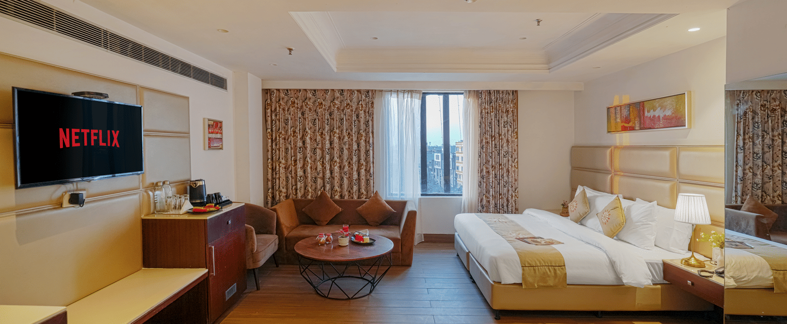 A hotel room featuring a bed and a separate seating area with a small, round coffee table and a velvet sofa at BluSalzz Select City Centre, Amritsar.