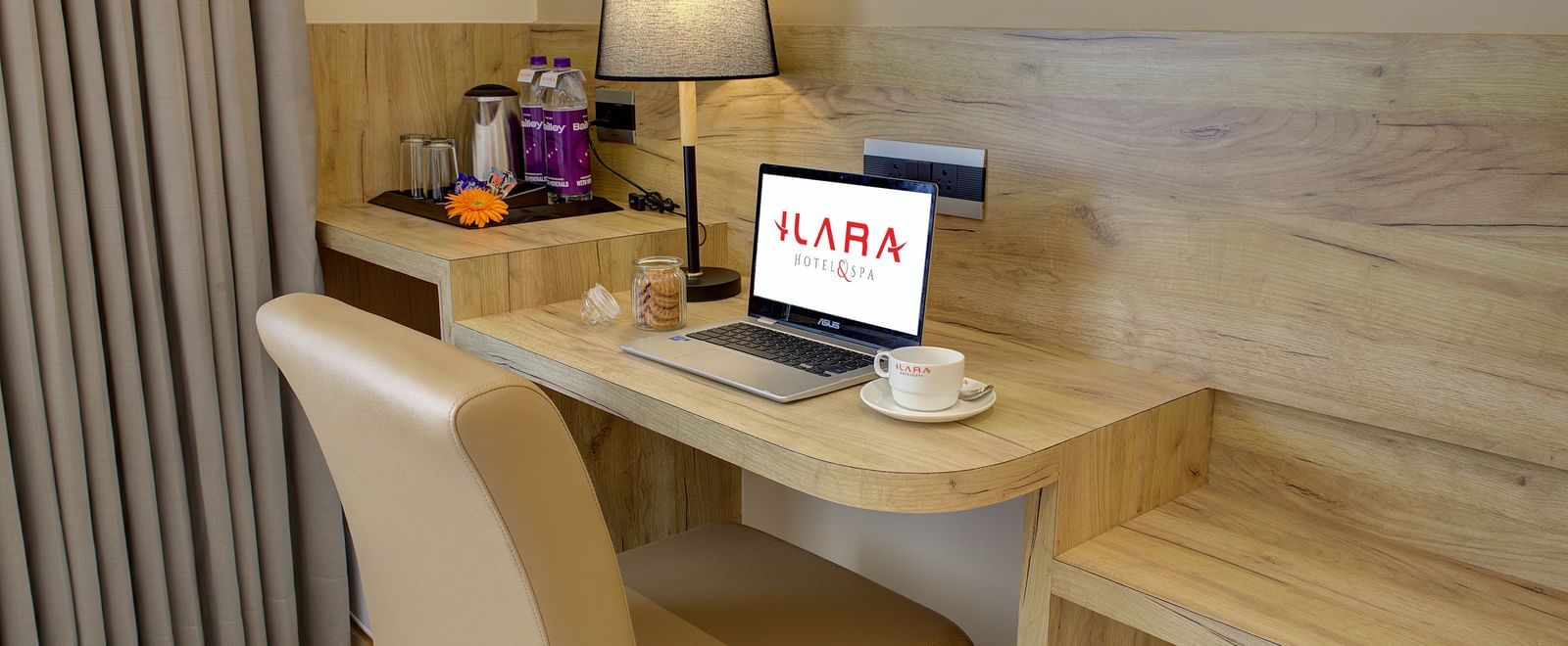 Close up shot of the work desk and chair with an open laptop kept on the desk alongside a coffee cup at the Junior Suite at Ilara Hotels & Spa, Tada.