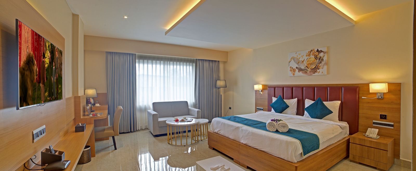 A brightly lit bedroom at the Junior Suite at Ilara Hotels & Spa, Tada with a double bed along with a bed side tables besides it.