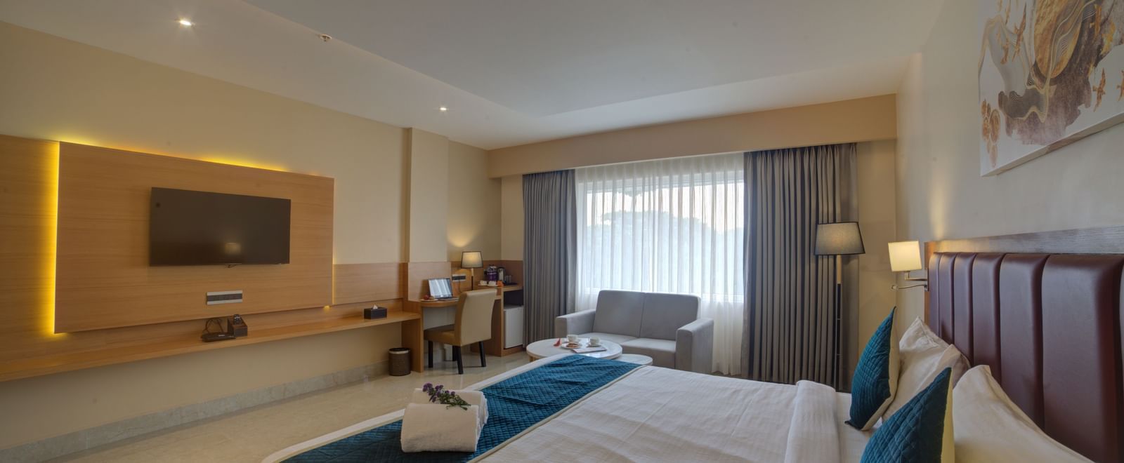 A wide angle shot of the Junior Suite with a double bed overlooking the wall mounted television at Ilara Hotels & Spa, Tada.