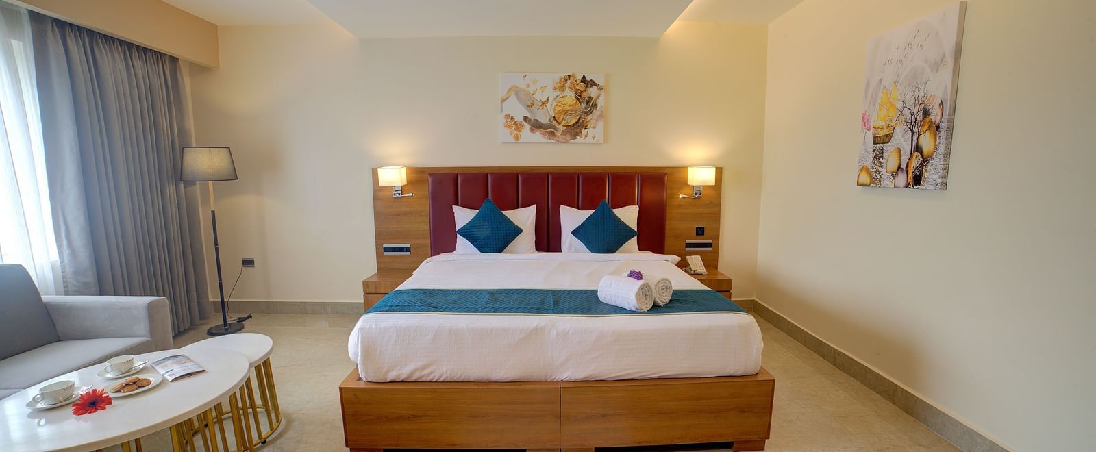 Front view shot of a comfortable double bed in the junior Suite with a common seating area besides it at Ilara Hotels & Spa, Tada.
