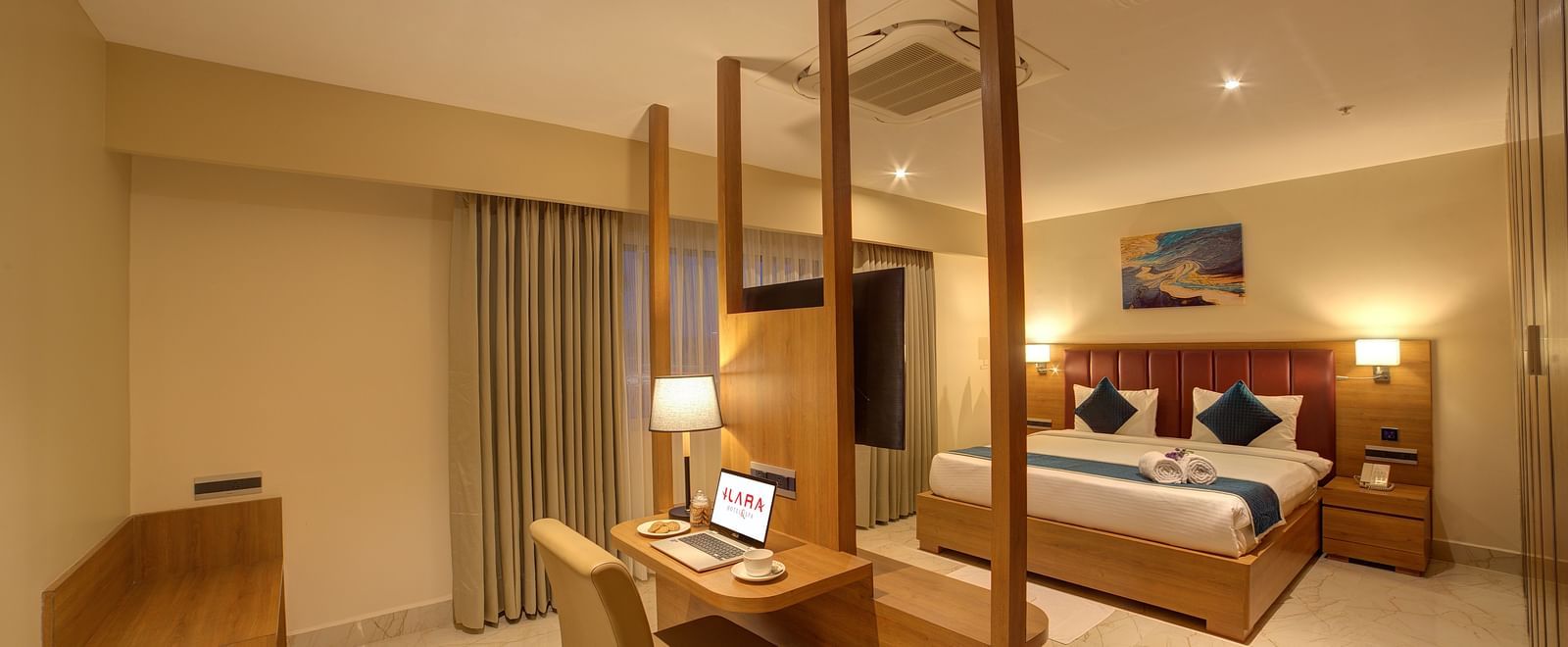 The bedroom of the Executive Suite with warm lighting along with a double bed and a work desk and chair in front of it at Ilara Hotels & Spa, Tada.