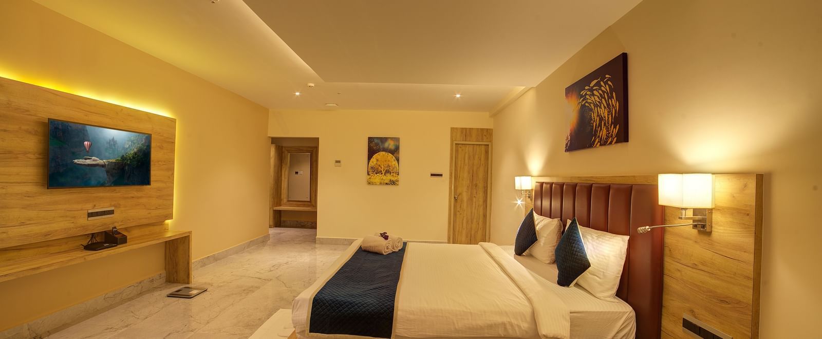 Side view shot of a double bed along in a warmly lit Junior Suite at Ilara Hotels & Spa, Tada with a false ceiling in the above it.