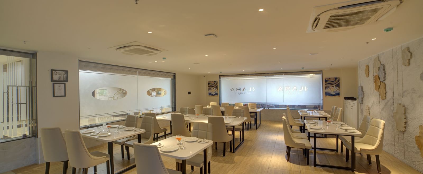 Full view shot of the Moti Mahal restaurant at Ilara Hotels & Spa, Tada with well arranged chairs and dining tables. 