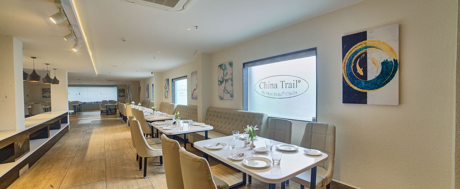 Side view of the seating area at the Moti Mahal restaurant with a wide translucent glass partition behind the tables at Ilara Hotels & Spa, Tada.