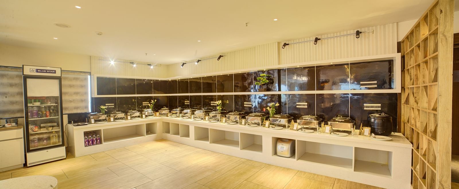 A wide angle shot of the Moti Mahal restaurant featuring a buffet counter in at the far end at Ilara Hotels & Spa, Tada.