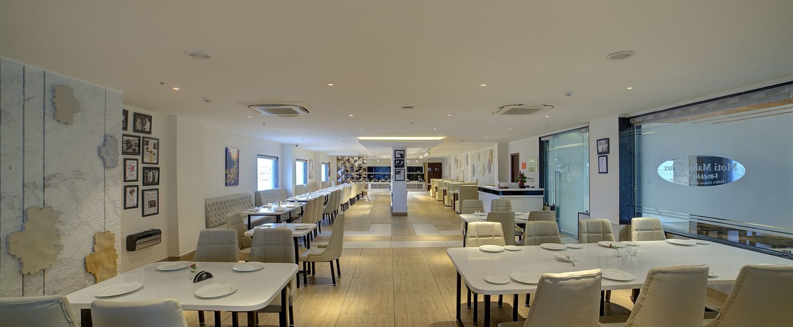 A pathway in the middle of the restaurant with dining tables and chairs in both sides of it at Ilara Hotels & Spa, Tada.