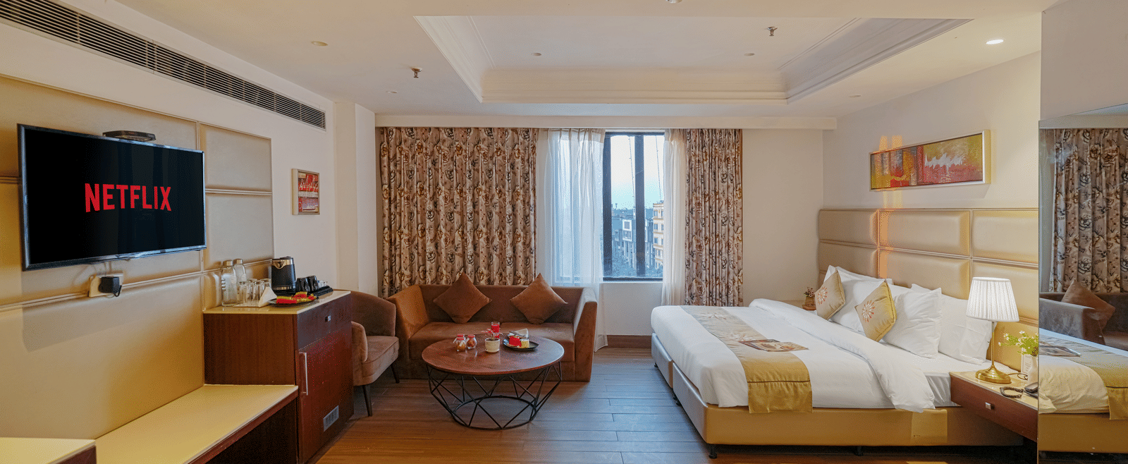 A hotel room featuring a bed and a separate seating area with a small, round coffee table and a velvet sofa at BluSalzz Select City Centre, Amritsar.