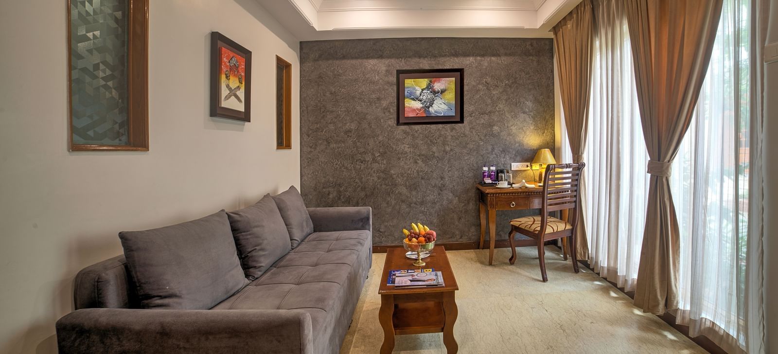 Bright and airy sitting area with sofa set, coffee table, and framed artwork at Ilara Hotels & Spa, OMR, Chennai