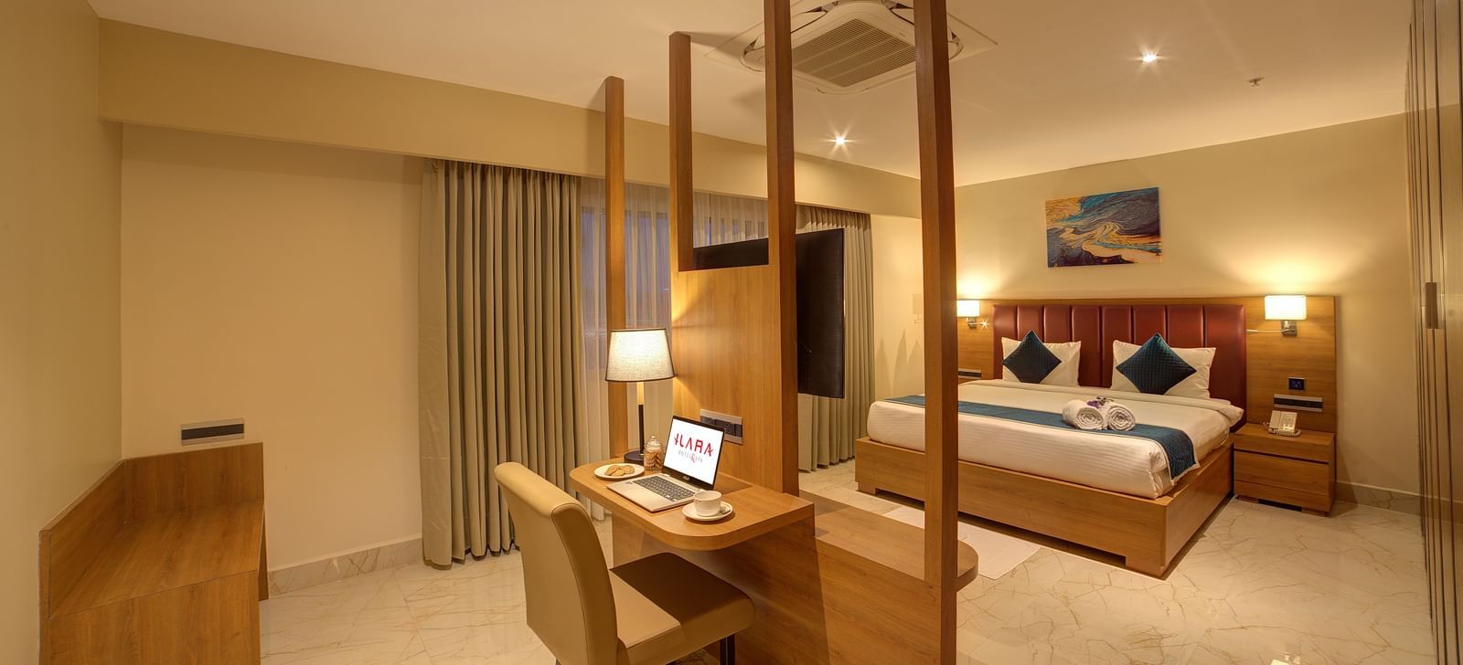 The bedroom of the Executive Suite with warm lighting along with a double bed and a work desk and chair in front of it at Ilara Hotels & Spa, Tada.