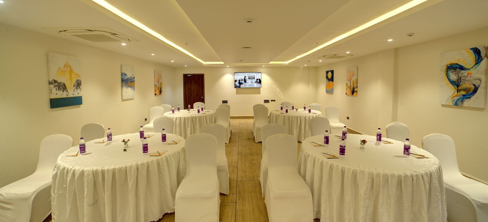 Front view shot of the banquet hall with several round tables with white table cloth surrounded by chairs at Ilara Hotels & Spa, Tada.