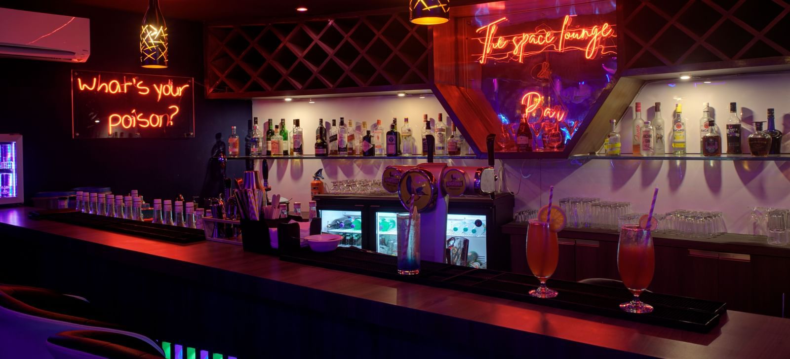 Stylish bar counter with colourful lighting and illuminated drink display at Ilara Hotels & Spa, OMR, Chennai