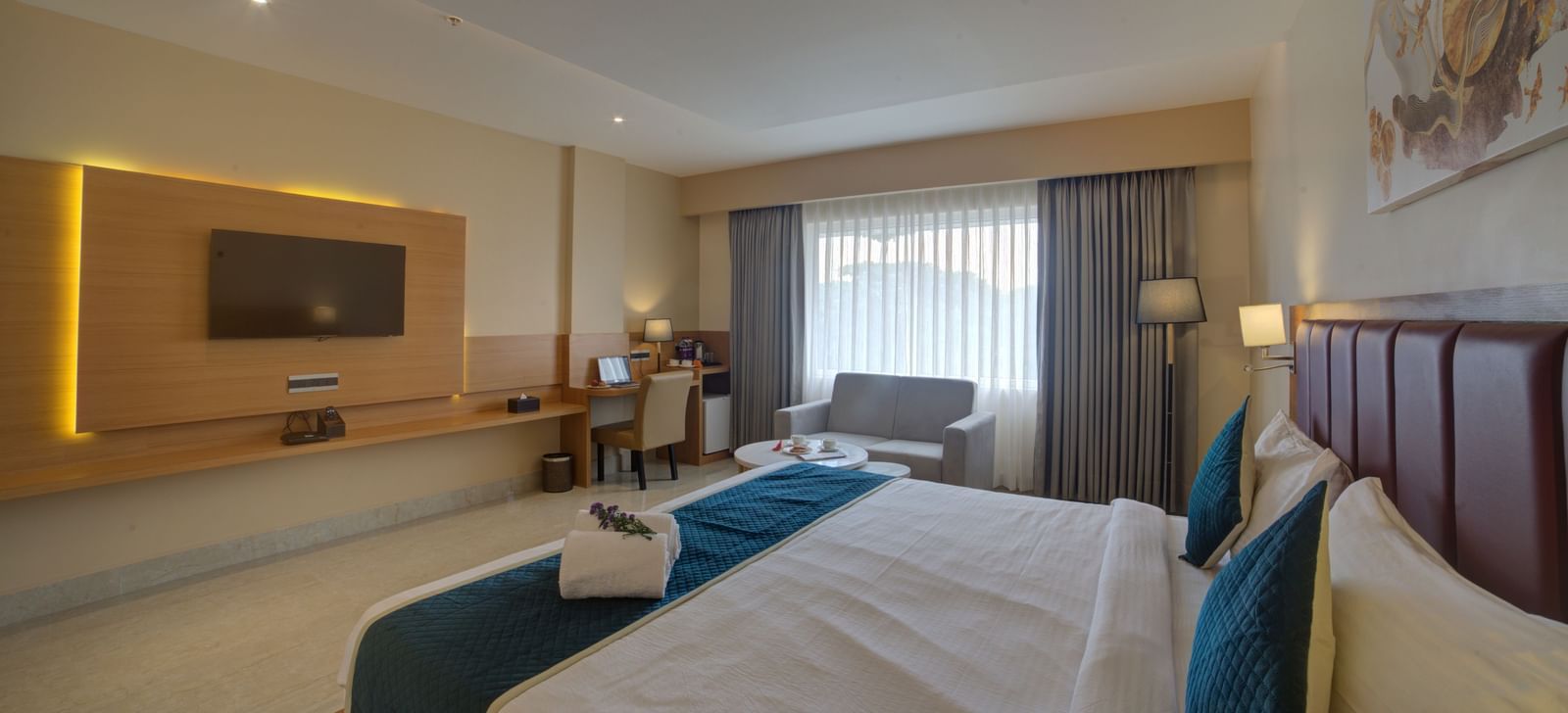 A wide angle shot of the Junior Suite with a double bed overlooking the wall mounted television at Ilara Hotels & Spa, Tada.