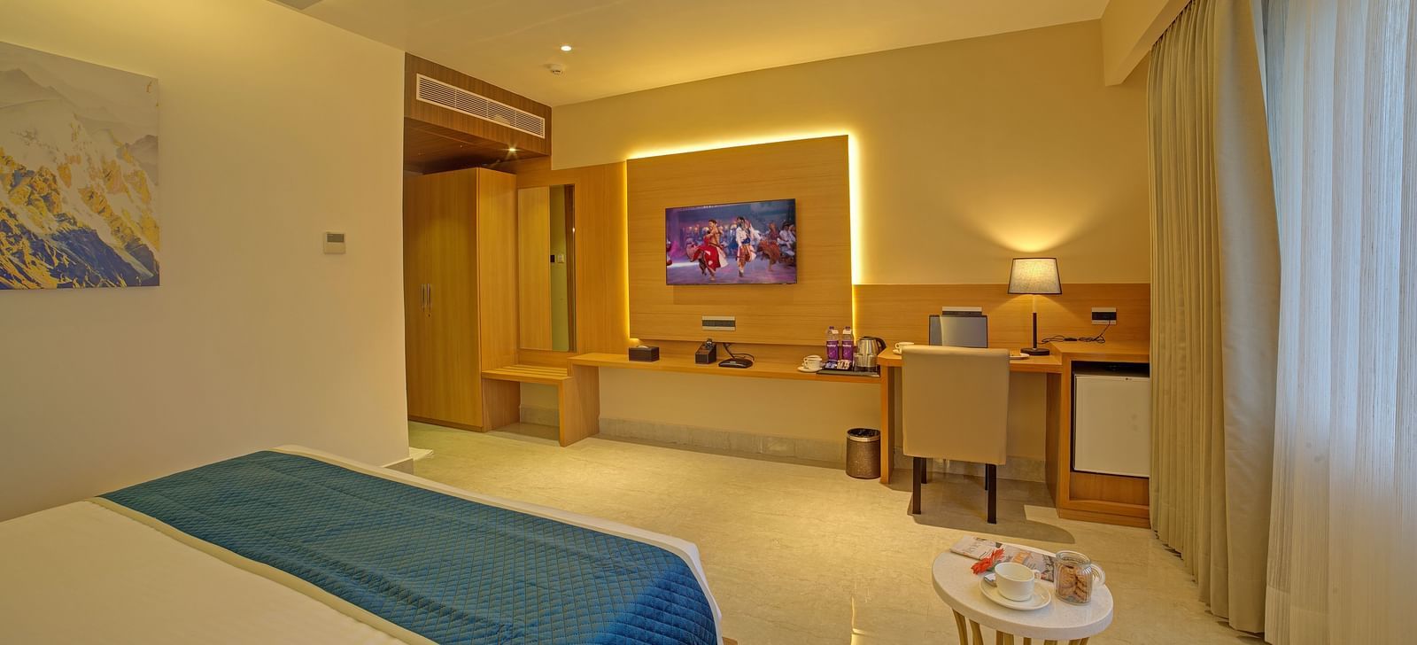 A wide angle shot of the Signature Suite at Ilara Hotels & Spa, Tada overlooking the television and the work desk and chair.