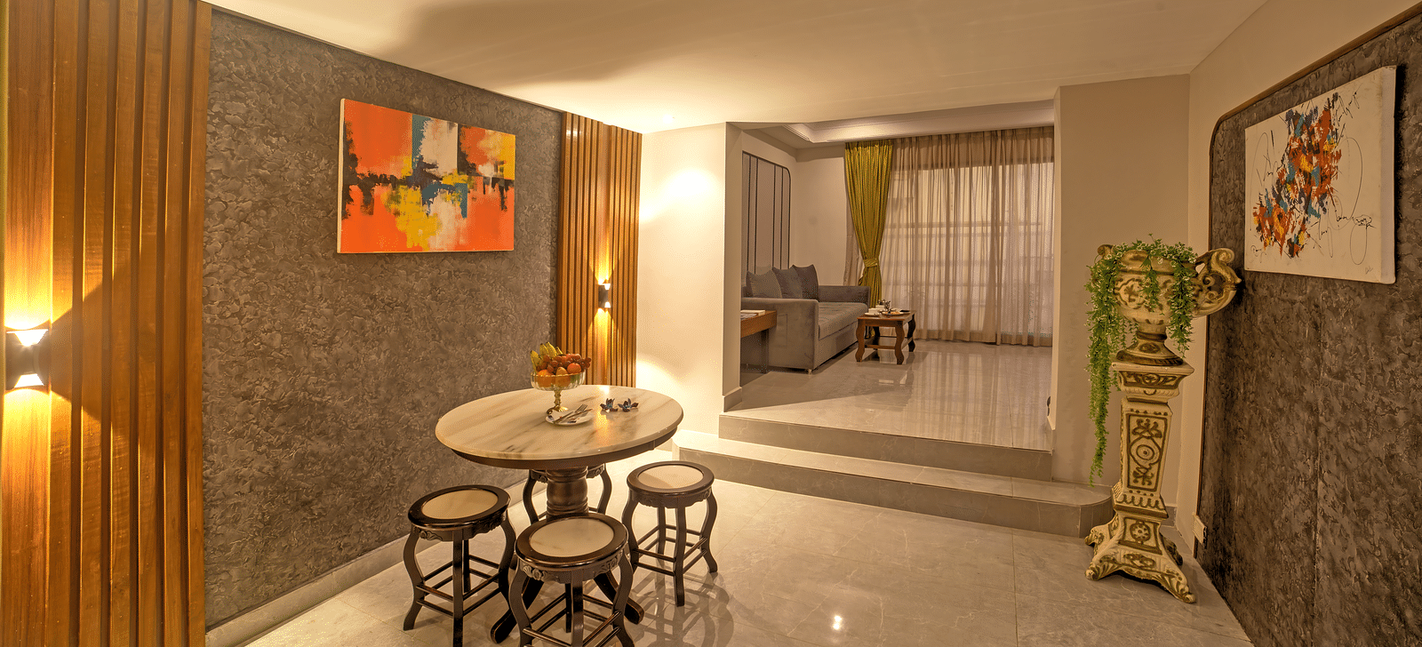 Cosy dining area with small round table, stools, and wall art in a softly lit corridor at Ilara Hotels & Spa, OMR, Chennai