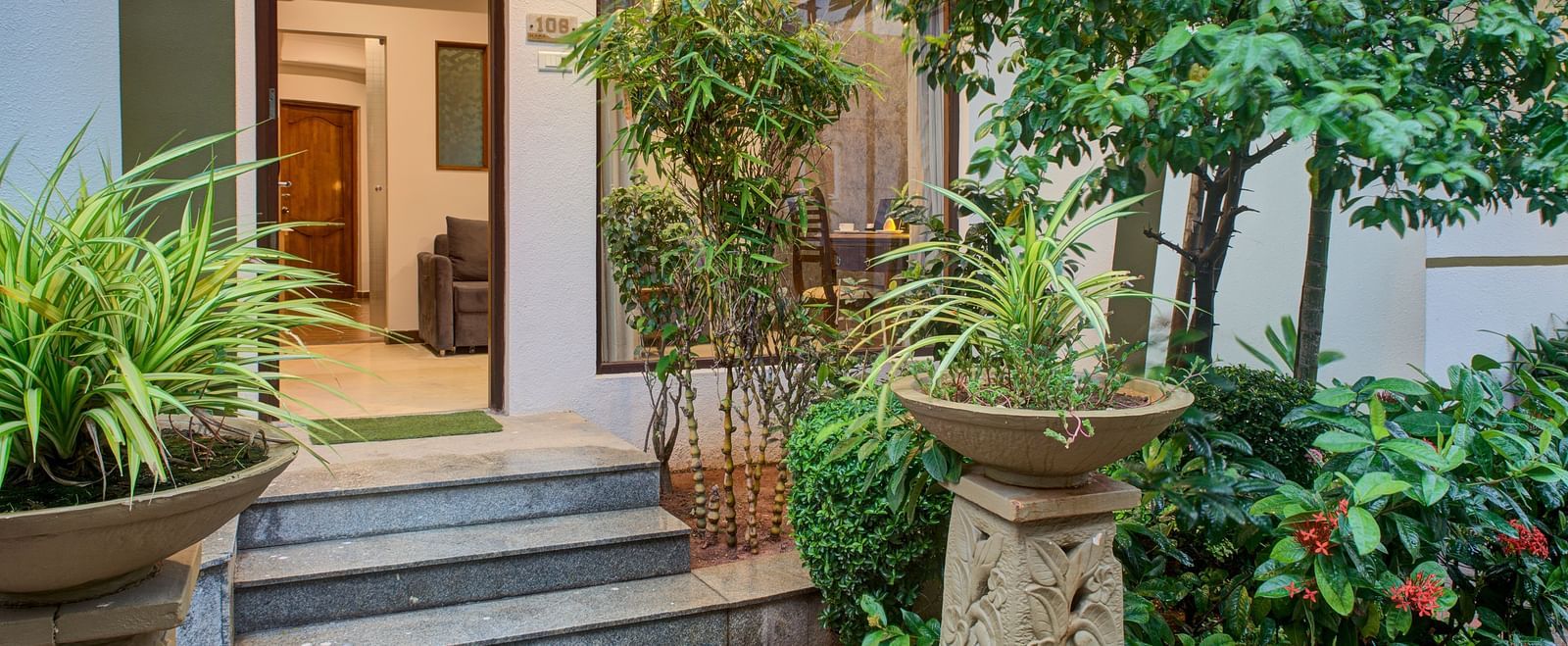 Charming entryway surrounded by lush green plants and stone decor at Ilara Hotels & Spa, OMR, Chennai