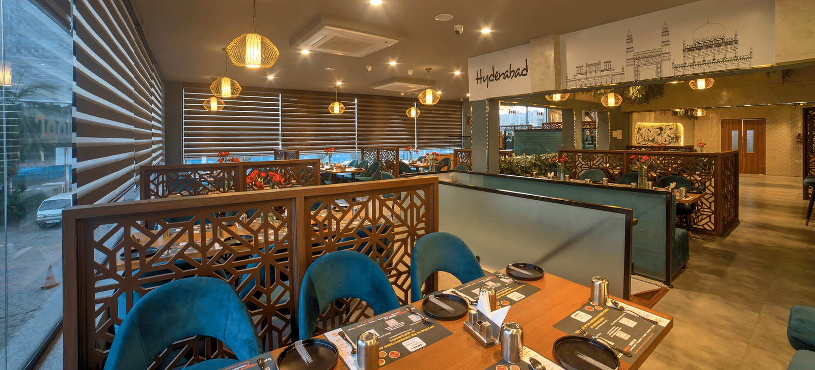 Wide-angle view of the restaurant with blue chairs and warm lighting at Ilara Hotels & Spa, OMR, Chennai