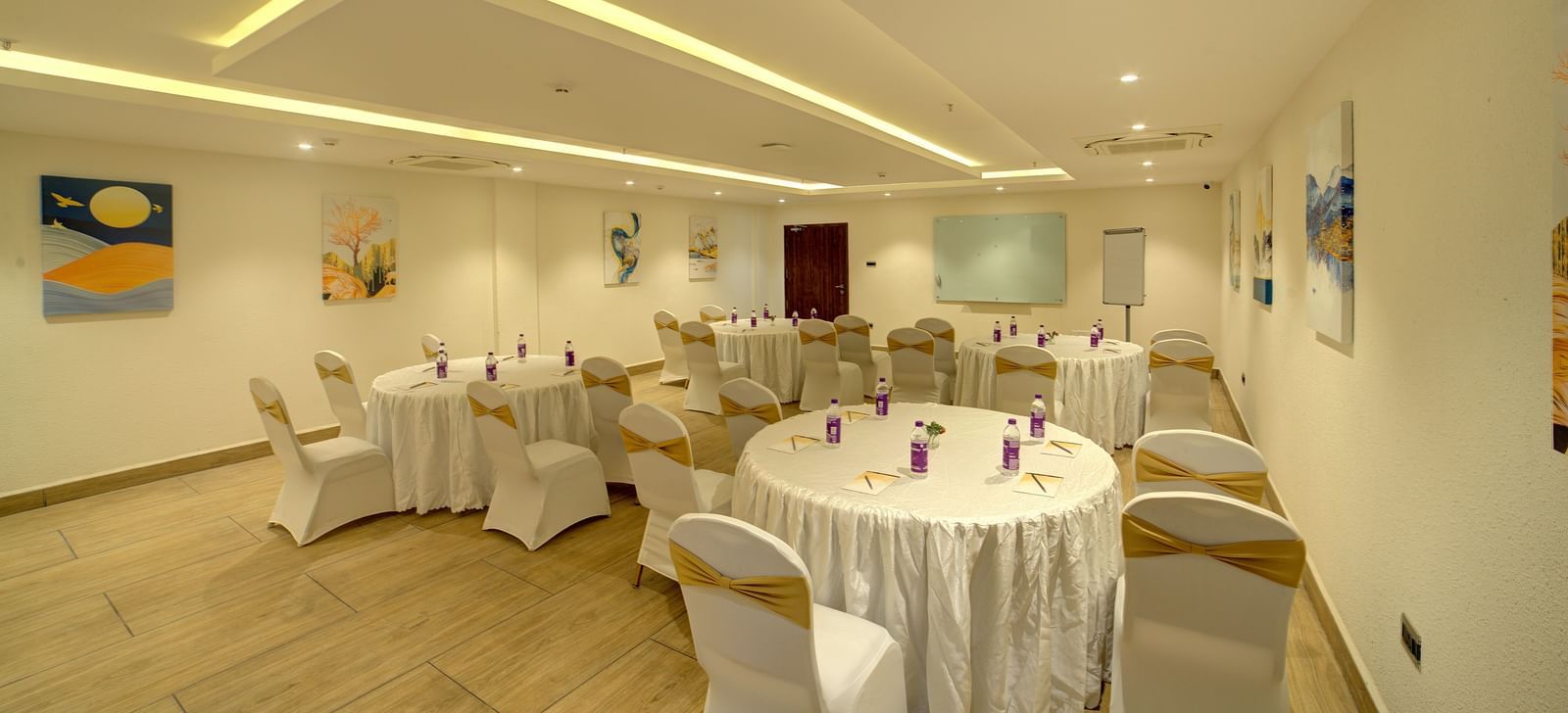 Corner view shot of a banquet hall with chairs and tables arranged for a fall event facing towards the projector at Ilara Hotels & Spa, Tada.
