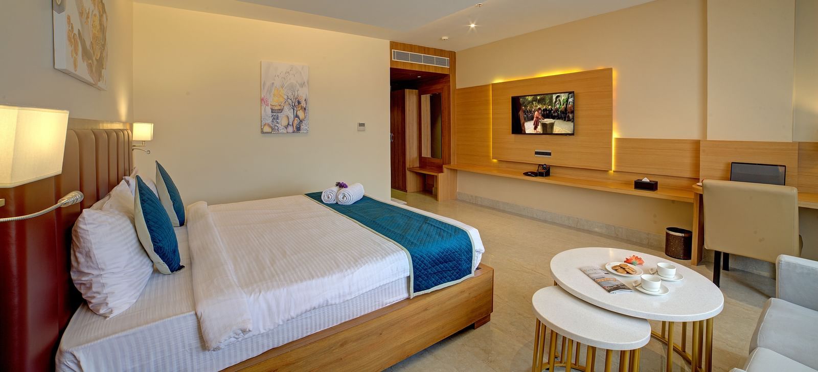 Corner view shot of the Junior Suite featuring a coffee table kept besides the double bed at Ilara Hotels & Spa, Tada.