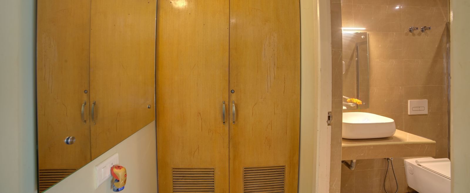Wood-panelled wardrobe with adjacent sink and vanity area at Ilara Hotels & Spa, OMR, Chennai