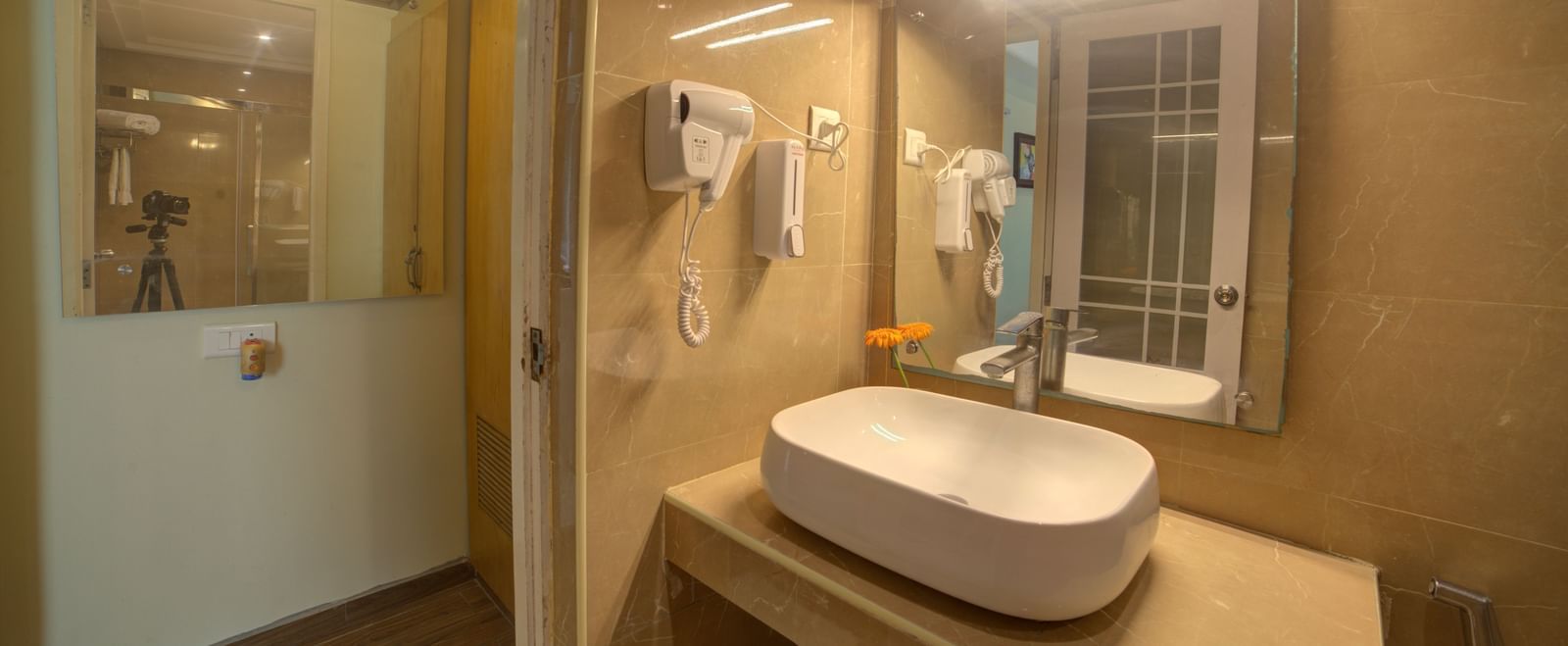 Elegant bathroom with twin mirrors, wash basin, and wall-mounted amenities at Ilara Hotels & Spa, OMR, Chennai