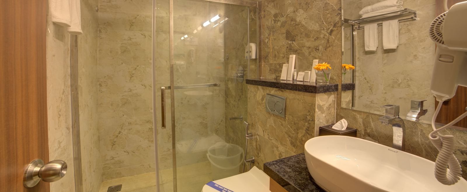 A bathroom fully equipped with essential toiletries besides a wash basin at Ilara Hotels & Spa, Tada.