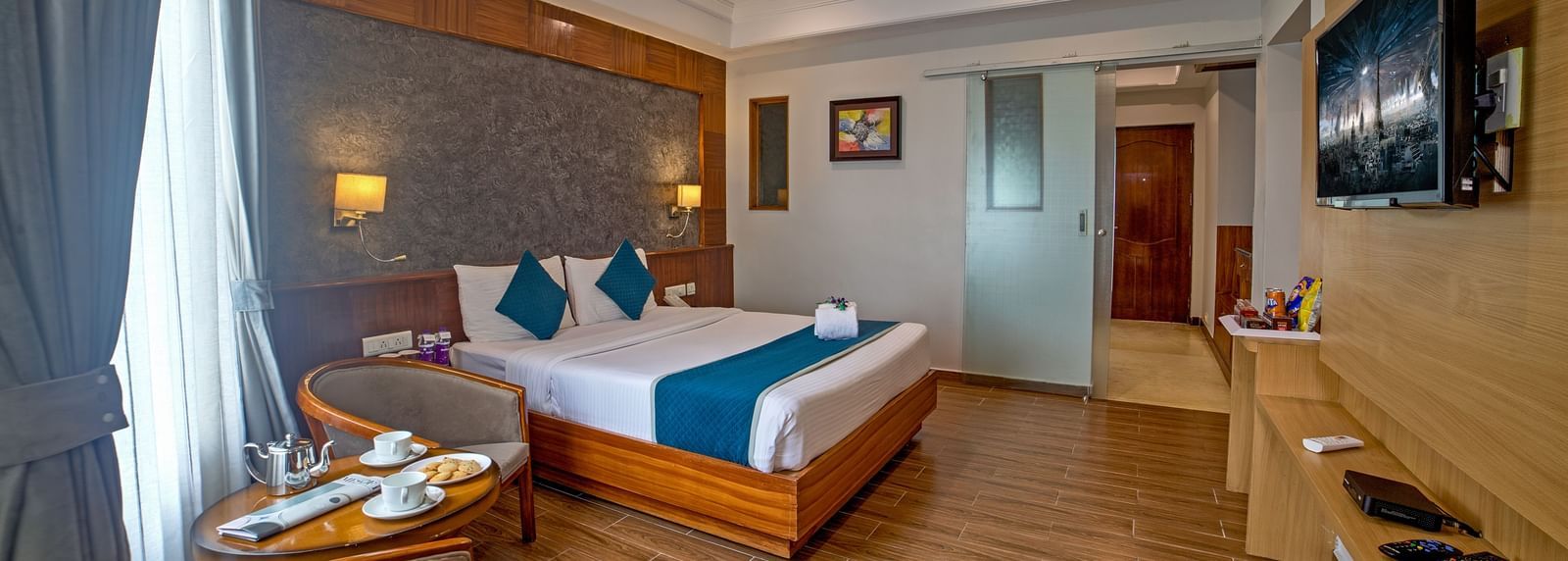 Well-appointed guest room with wooden flooring, modern furnishings, and a cosy seating area at Ilara Hotels & Spa, OMR, Chennai