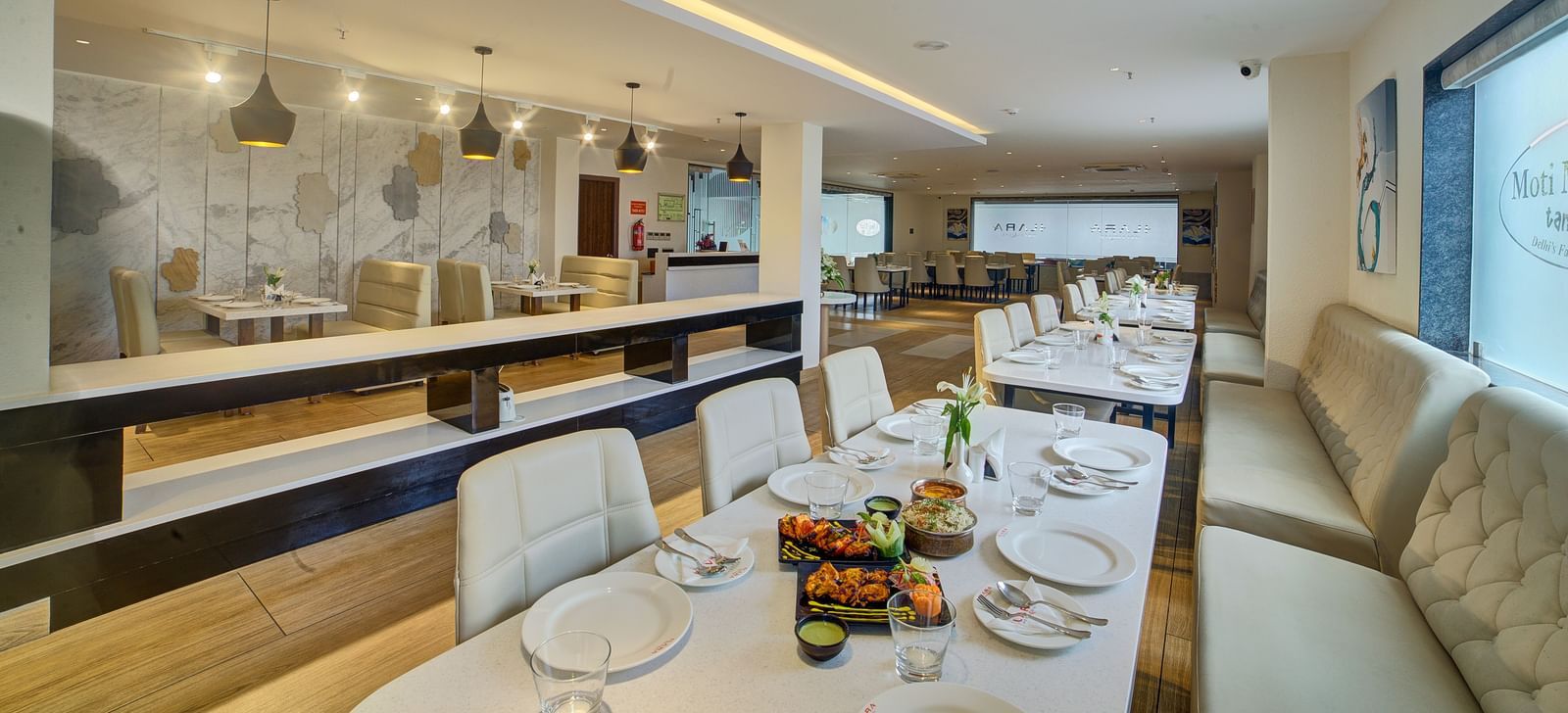 The interiors of a brightly lit dining area with beautifully served dishes on the table at Ilara Hotels & Spa, Tada.