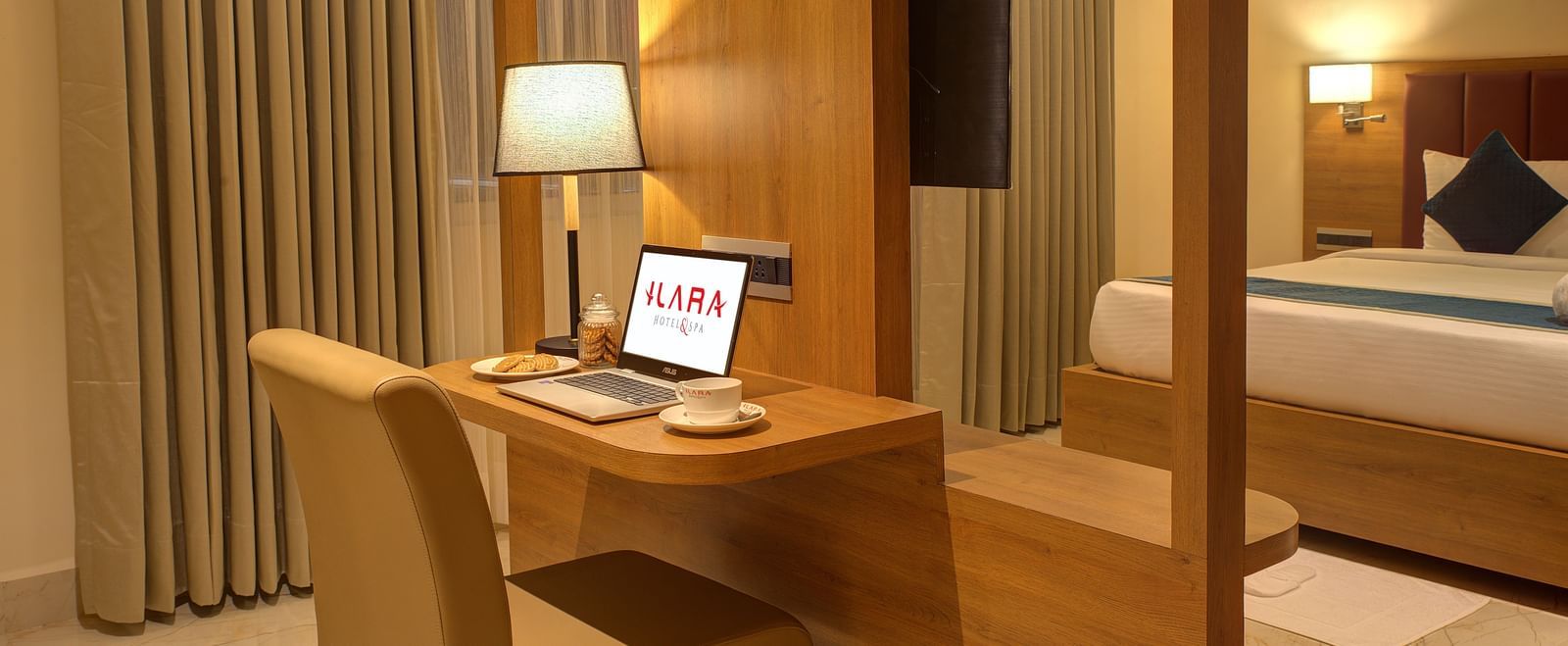Corner view close up shot of the work station in the bedroom of the Executive Suite with a laptop and a table lamp kept on the desk at Ilara Hotels & Spa, Tada.