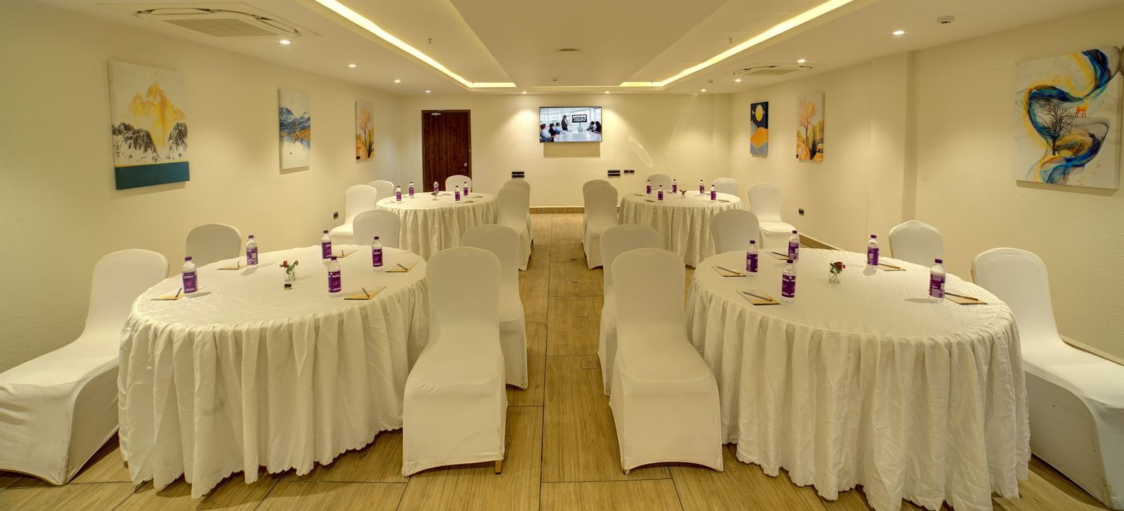 Front view shot of the banquet hall with several round tables with white table cloth surrounded by chairs at Ilara Hotels & Spa, Tada.