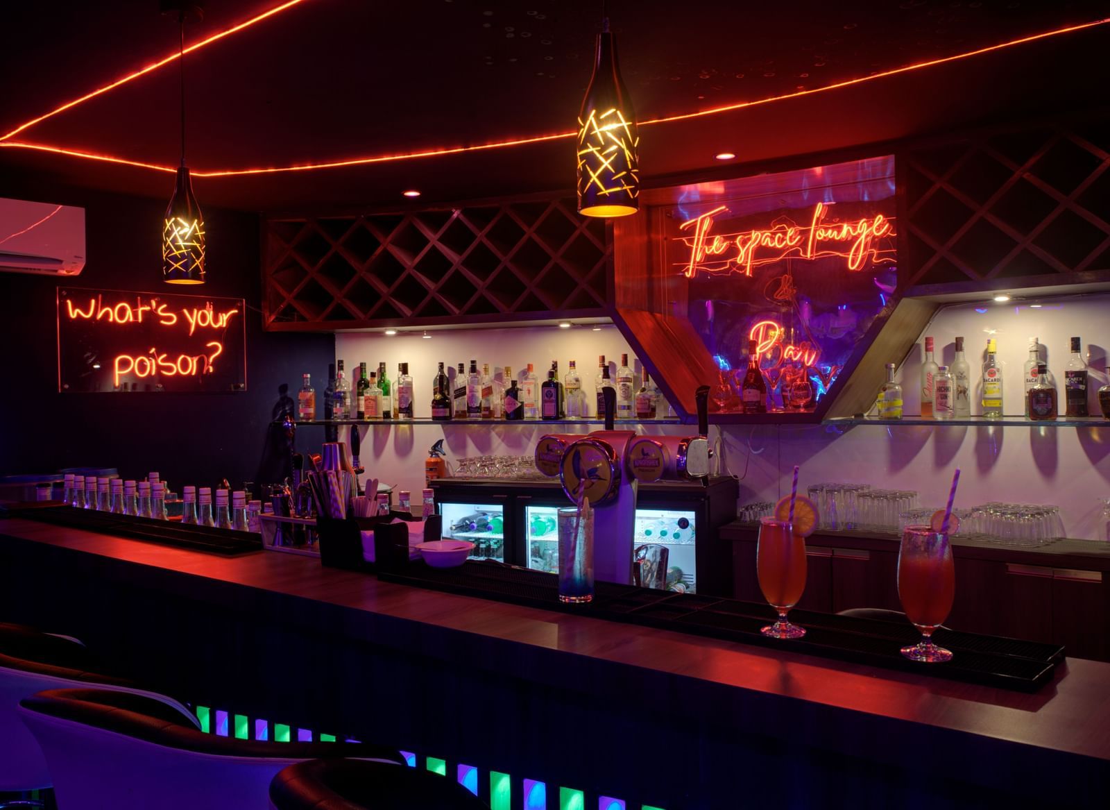 Stylish bar counter with colourful lighting and illuminated drink display at Ilara Hotels & Spa, OMR, Chennai