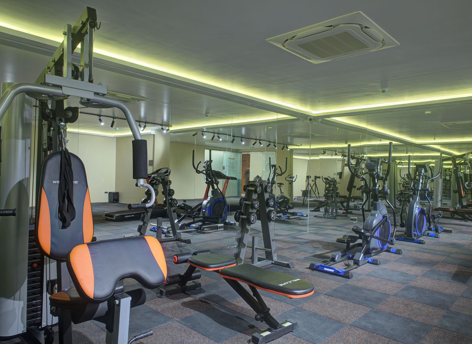 A wide view of the fitness centre with various gym equipment and modern lighting at Ilara Hotels & Spa, Tada.