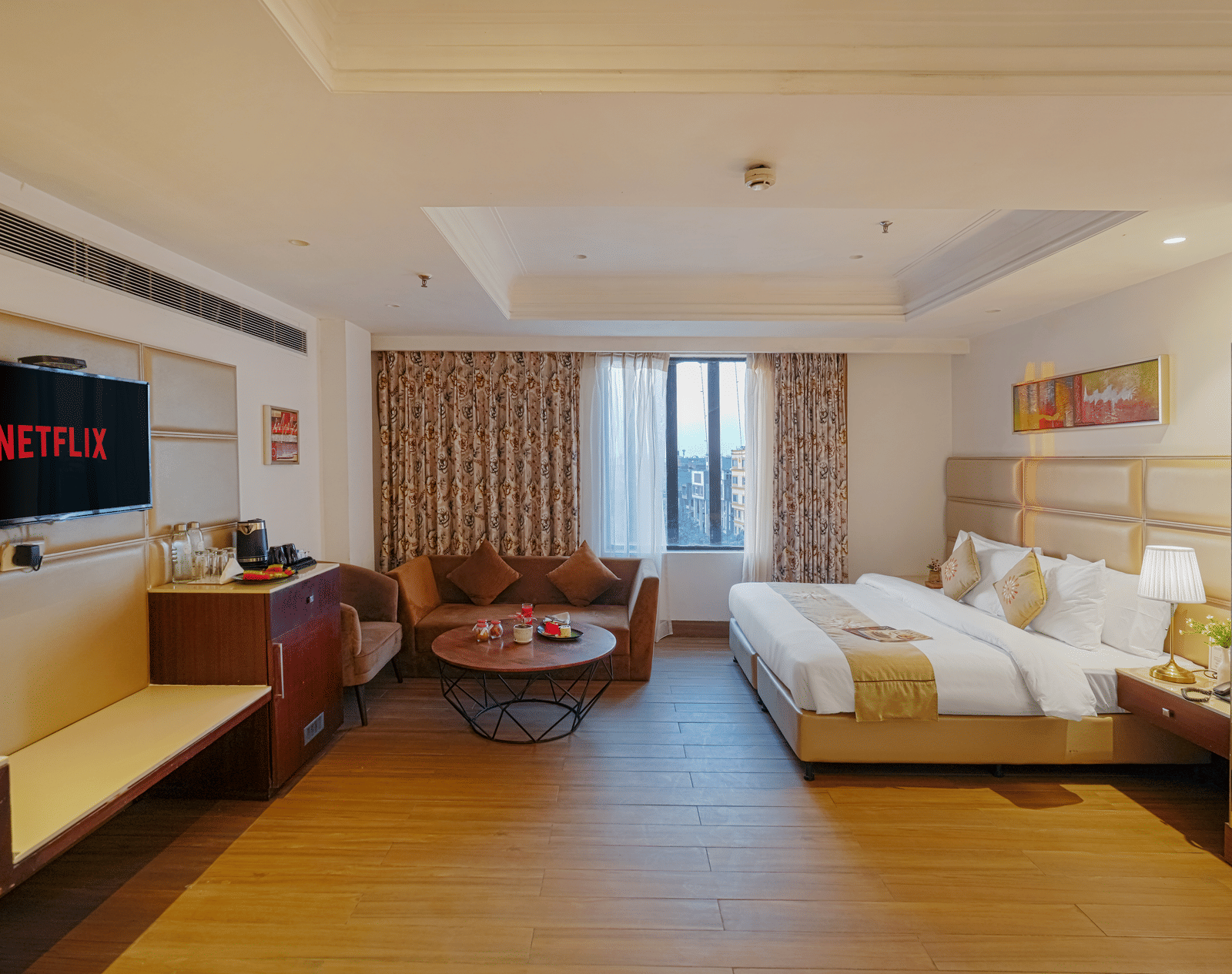 A hotel room featuring a bed and a separate seating area with a small, round coffee table and a velvet sofa at BluSalzz Select City Centre, Amritsar.