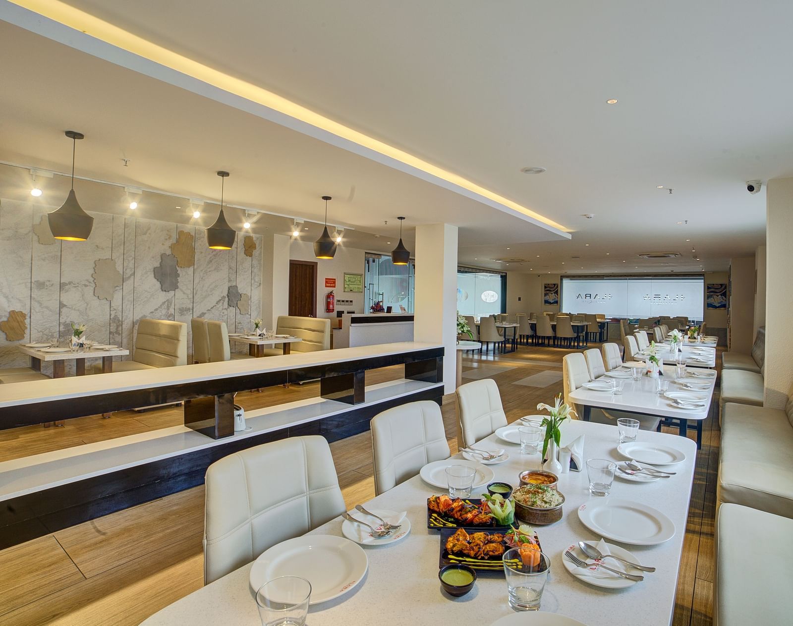 The interiors of a brightly lit dining area with beautifully served dishes on the table at Ilara Hotels & Spa, Tada.