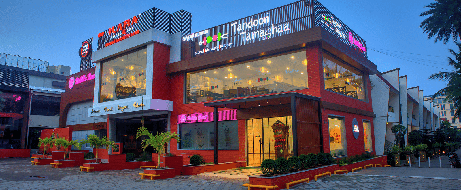 Exterior view of Tandoori Tamashaa building lit up in the evening at Ilara Hotels & Spa, OMR, Chennai
