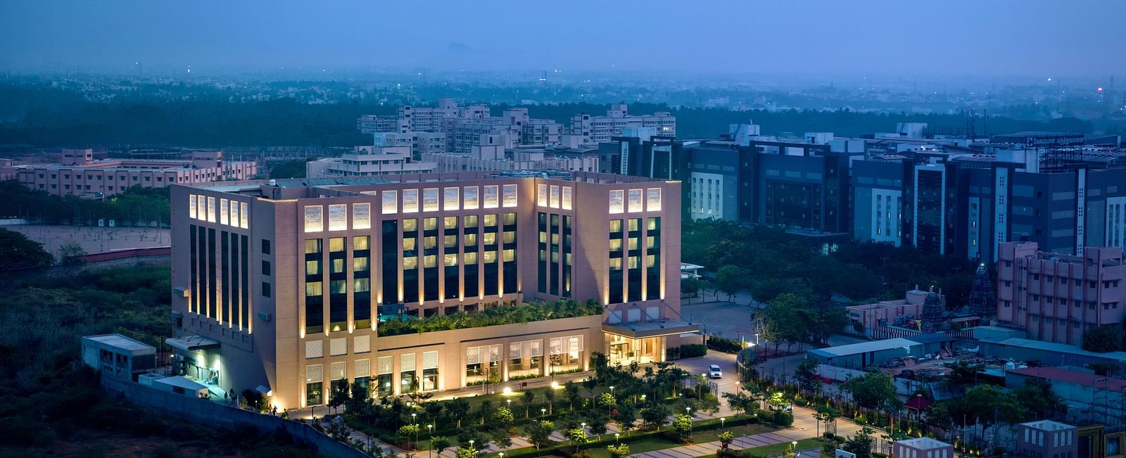 An aerial shot of the grand hotel, highlighting its extensive gardens and well-lit exterior - Grand Madurai by GRT Hotels