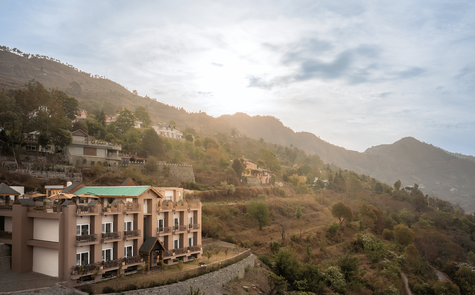 facade of the Leisure hotel surrounded by greenery with hills on the background during day v