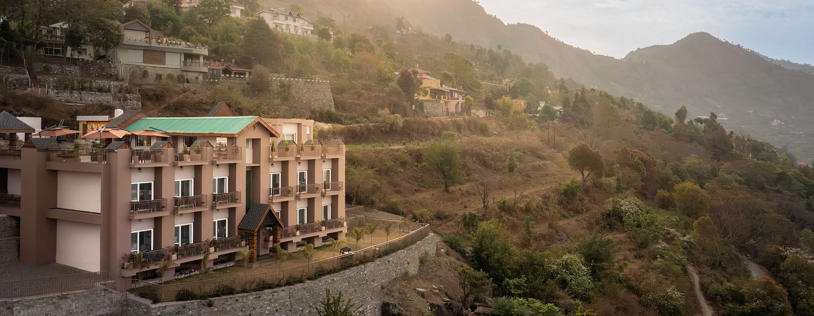 facade of the Leisure hotel surrounded by greenery with hills on the background during day v