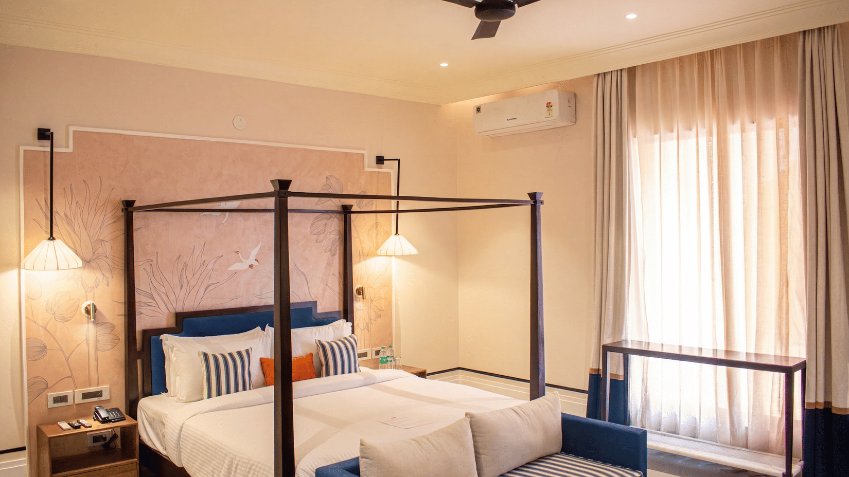 Another view of a bedroom with a four poster king size bed, attached sofa, bedside table, lamp, and curtains at The Sierra - By The Lake.
