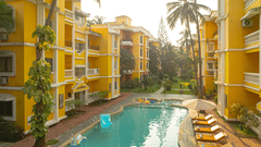 An image of an outdoor swimming pool framed by vibrant yellow buildings.
