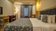Standard room featuring a patterned bedspread, work desk, and ambient lighting at Golden Tulip, Udaipur.