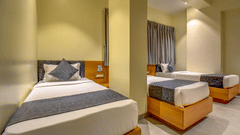 Room with wooden beds, bedside tables, and soft lighting at VITS Select Nashik Hotels & Resorts.