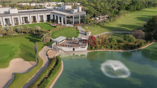 aerial view of a building next to a waterbody with fountains - Karma Lakelands.