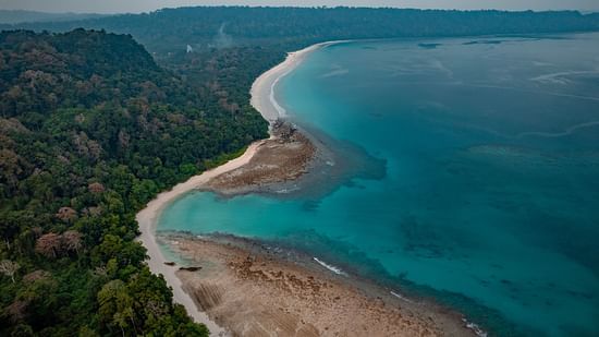 A coastal stretch enveloped by towering mountains.