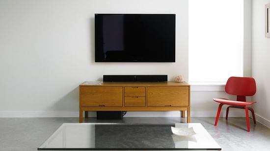 a room with wooden furniture and a TV table and an LCD TV on the wall