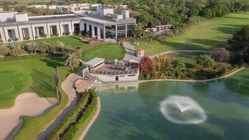 aerial view of a building next to a waterbody with fountains - Karma Lakelands.