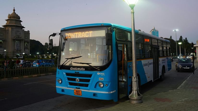  City bus stationed on a broad road near a landmark structure, captured during early evening hours.