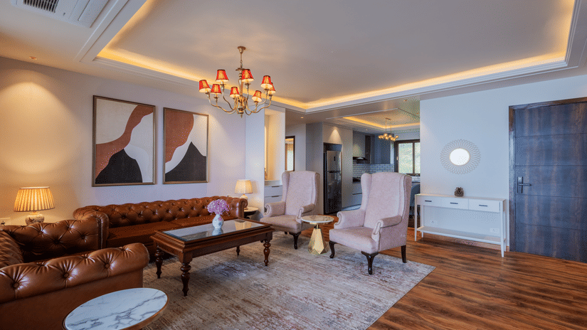 A modern living room in the Premium Apartment at The Manor Luxury Apartment featuring elegant furnishings, a chandelier, and a neatly placed rug.